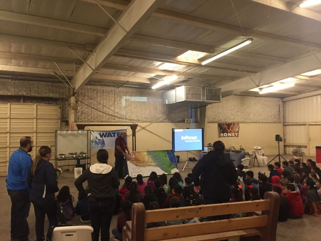 Jaime Flores, watershed coordinator, explains some the watershed model to students at a Kids, Kows and More event.