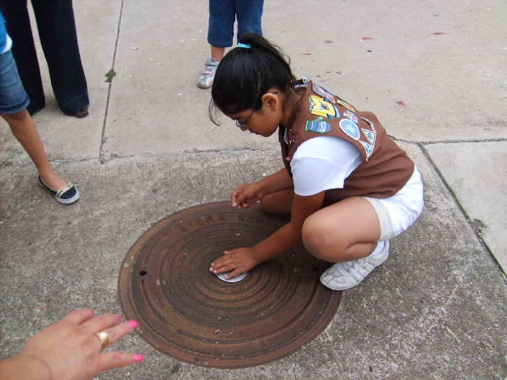 Brownie troop member installing storm drain marker